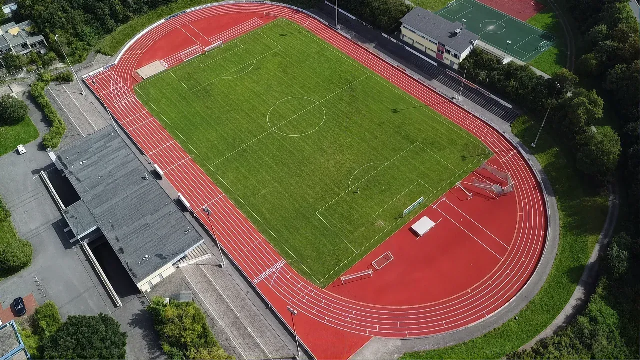 Luftaufnahme einer Leichtathletikanlage mit rotem Kunststoffbelag und Rasenspielfeld